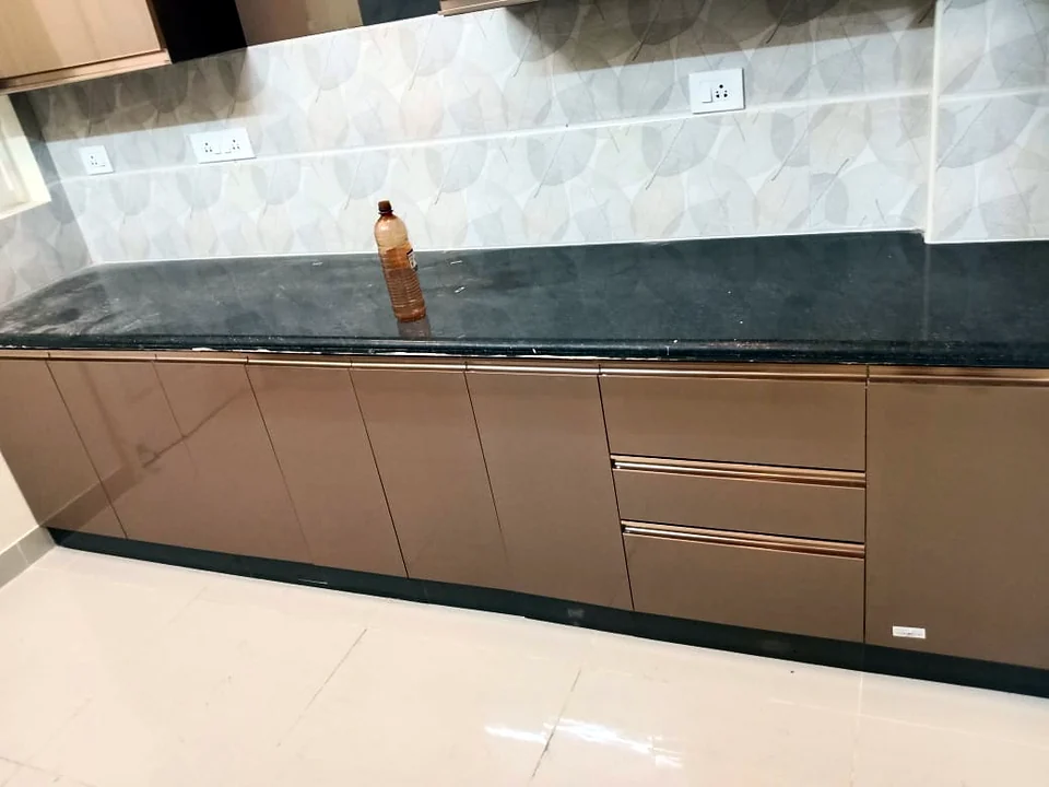 Modular kitchen with bronze handleless drawers and patterned tile backsplash by Wood Crops, Chennai