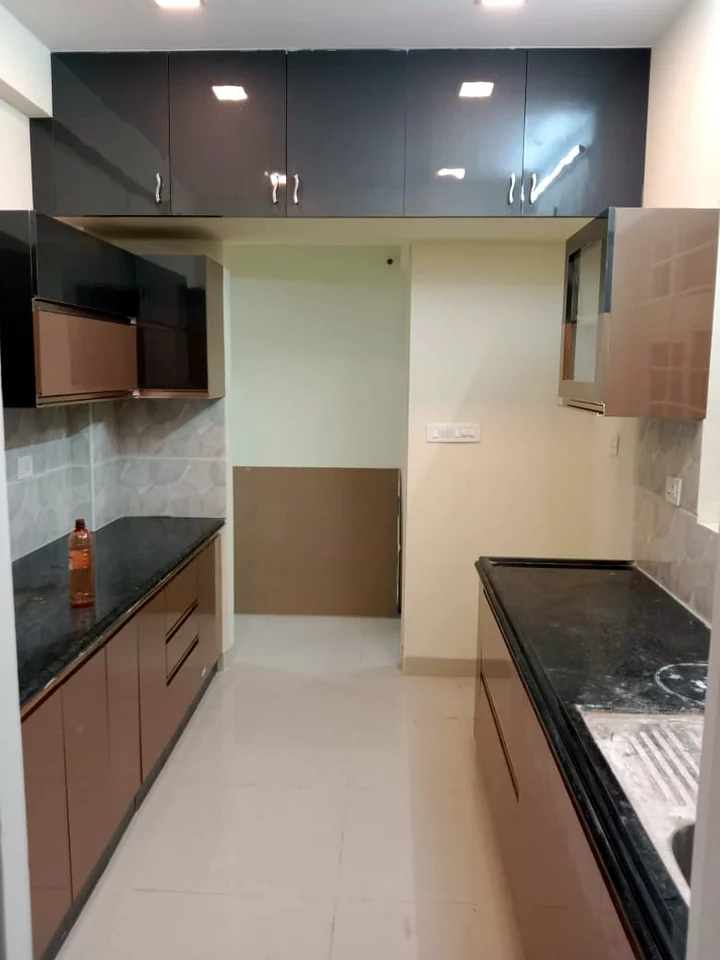 Parallel modular kitchen with wood-finish cabinets and black granite counter by Wood Crops, Chennai