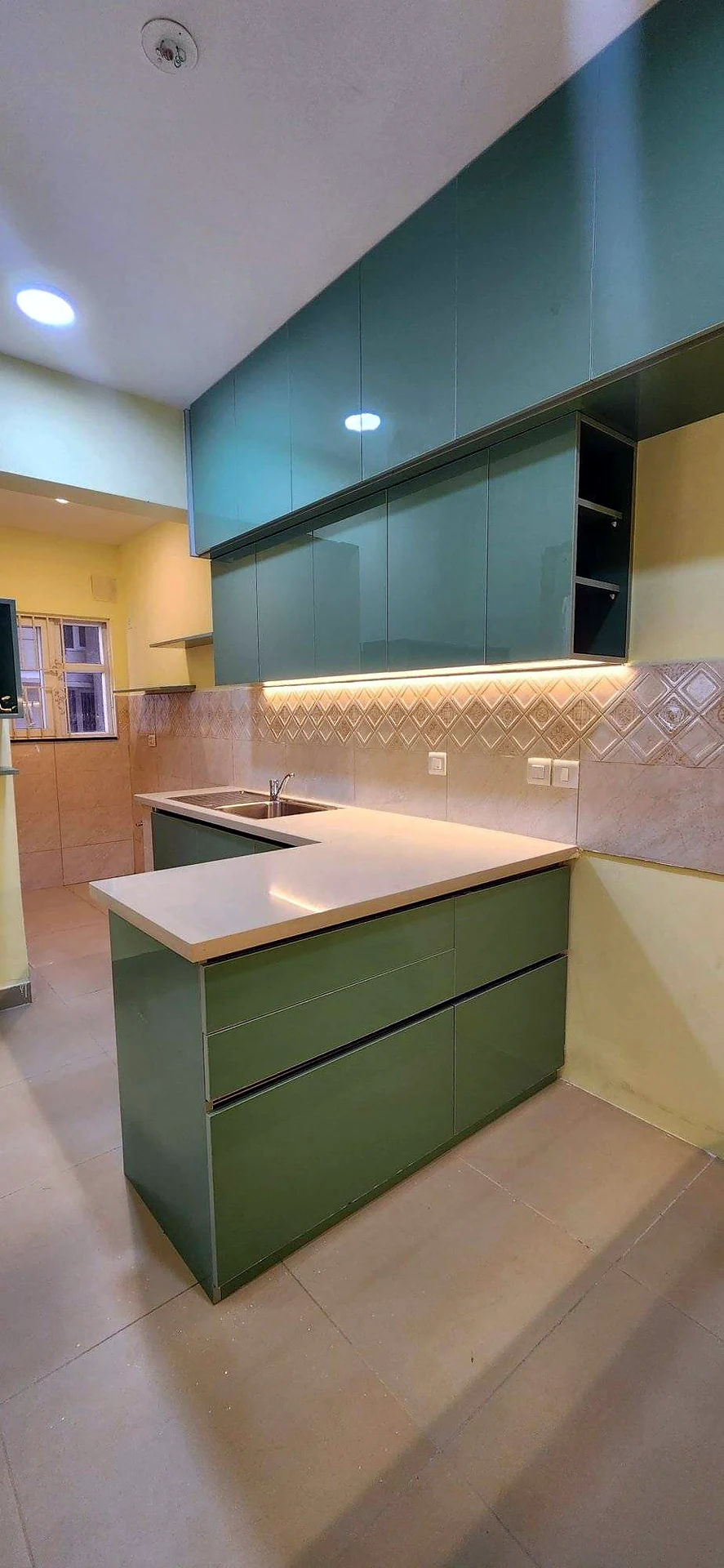 Sage green modular kitchen with breakfast counter, quartz top and under-cabinet lighting, designed and built by Wood Crops, Chennai