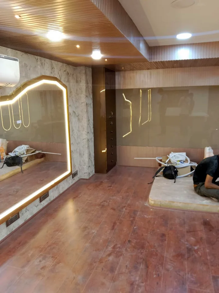 Salon wall with LED-framed mirror and marble-look cladding by Wood Crops, Chennai