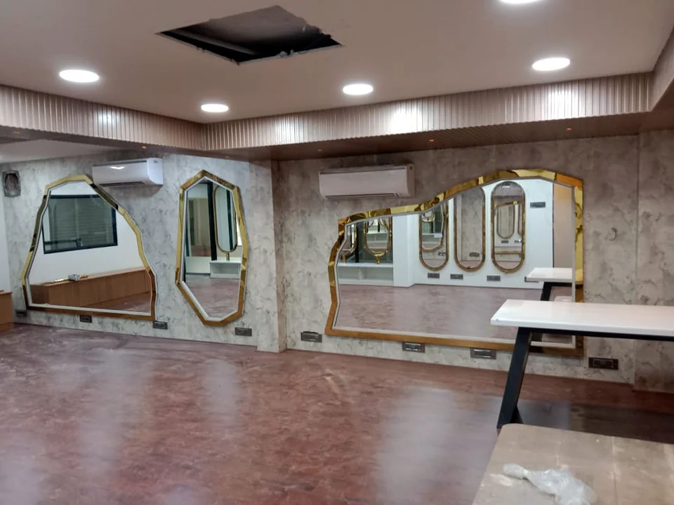 Salon interior with sculpted gold-edged mirrors on stone-look walls by Wood Crops, Chennai